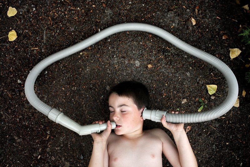 Strike a pose: Mr Archibald said that when he took the photographs Elijah would often do the unexpected with props he found lying around - here he plays with a vacuum pipe held to his ear and lips